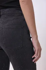 Pantalón de jean negro de corte recto con sutiles detalles de brillo en toda la prenda. Presenta tiro alto, cierre frontal con botón y bolsillos laterales y traseros.