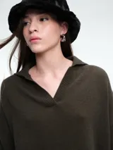 Sweater de punto color verde oliva, con cuello polo abierto en V, manga larga con hombros caídos y terminaciones acanaladas en puños y ruedo.