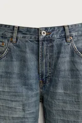 Jeans flare fit de denim rígido en color azul con efecto lavado. Presentan tiro medio, diseño de cinco bolsillos y cierre frontal con cremallera y botón.
