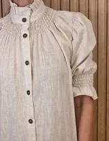 Vestido midi marrón con textura sutil, cuello alto fruncido, cierre frontal con botones y mangas cortas abullonadas con elástico.