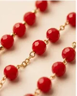 Collar rosario de acero con baño de oro, compuesto por cuentas de cristal rojo y un dije de San Benito con cruz colgante.