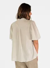 Blusa de algodón color azul marino con textura de pequeños puntos en relieve, cuello en V y mangas cortas abullonadas con puños elásticos.
