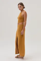 Top halter tejido texturizado en tono mostaza con tiras finas que se atan en la espalda.