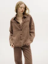 Campera de denim con efecto gastado, cuello camisero, cierre frontal con botones metálicos y corte holgado. Presenta canesú con costuras decorativas en el frente y la espalda, y botones en los puños.