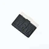 Billetera negra de cuero sintético con diseño acolchado y cierre con broche a presión.