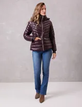 Campera puffer de acabado satinado en color marrón oscuro. Presenta un diseño capitoneado con líneas en V, cierre frontal metálico, capucha fija y puños internos de tejido elastizado con abertura para el pulgar. Incluye bolsillos laterales con cierre invisible y logo metálico en la manga.