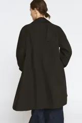 Trench oversize color negro de la colección Zara Woman, confeccionado en hilatura con mezcla de algodón. Presenta cuello solapa, manga larga ajustable con trabillas, bolsillos delanteros y cierre frontal con botones.