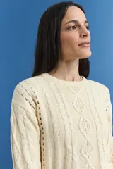 Sweater de tejido de punto color crema, con diseño de ochos y detalles calados. Presenta escote redondo a la base, mangas largas y corte recto.