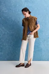 Chaleco de algodón color beige, de calce relajado, con cuello clásico, hombros amplios, cierre frontal con broches metálicos y bolsillos delanteros con solapa.