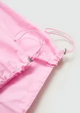 Pantalon estilo parachute de color rosado, con cintura elástica y bajos ajustables mediante cordones. Presenta un diseño holgado con bolsillos laterales.