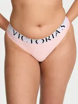 Tanga de tiro bajo confeccionada en microfibra suave color rosado, con cintura elástica ancha en color blanco y el logotipo de Victoria's Secret impreso en negro.