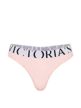 Tanga de tiro bajo confeccionada en microfibra suave color rosado, con cintura elástica ancha en color blanco y el logotipo de Victoria's Secret impreso en negro.