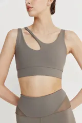 Top deportivo asimétrico color gris topo, realizado en tela doble y cintura elástica para mayor compresión y sujeción.