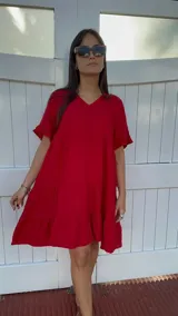Vestido corto rojo con escote en V, mangas cortas con volados y corte escalonado.