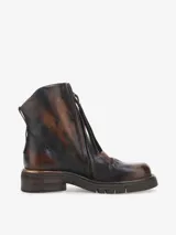 Bota corta de cuero bovino, color negro con efecto desgastado o metalizado grisáceo. Presenta cierre lateral con tirador y suela gruesa de goma con relieve.