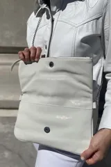 Sobre de cuero con textura efecto reptil en color marrón. Cuenta con una solapa frontal con cierre metálico y una correa de cadena plateada extraíble.