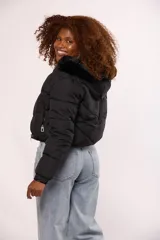 Campera bomber de nylon color rosado, con diseño acolchado, cierre frontal con cremallera y botones a presión, y capucha con borde de piel sintética al tono.