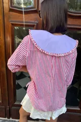 Camisa de mangas 3/4 abullonadas con cuello bebé removible, a rayas verticales rojas y blancas.