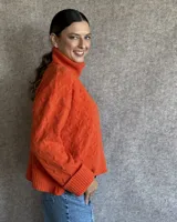 Sweater de lana color crudo con cuello alto y diseño trenzado.