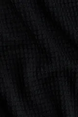 Top en punto negro con textura, escote bote y mangas murciélago cortas.