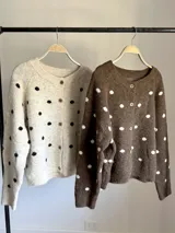 Cardigan tejido de punto con diseño de lunares, cuello redondo y cierre frontal con botones. Presenta un corte holgado y mangas largas.