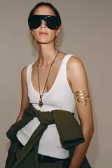 Collar de cordón fino color marrón con dije metálico dorado en forma de serpiente geométrica. Posee un sistema de cierre ajustable con pieza circular.