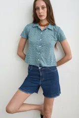 Camisa de broderie color celeste, con cuello camisero, manga corta y cierre frontal con botones de nácar.