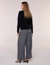 Buzo de punto fino color gris, de calce relajado, escote redondo amplio y canesú con textura acanalada. Cuenta con apliques de tachas metálicas doradas en la línea del hombro, mangas largas de hombro caído y puños y ruedo acanalados.