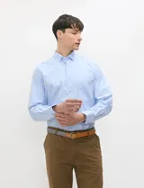 Camisa de manga larga de tejido Oxford color celeste, con cuello button-down, cierre frontal de botones y un bolsillo aplicado en el pecho.