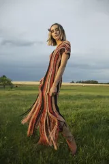 Vestido largo de crochet con lurex, diseño a rayas verticales en tonos beige y negro, con flecos en el ruedo.