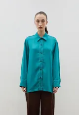 Camisa de corte holgado y diseño clásico, confeccionada en tela satinada con un sutil estampado floral tono sobre tono. Presenta cuello camisero, cierre frontal con botones y mangas largas con puños rectos.