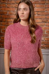 Sweater de punto de manga corta en color rosa con destellos dorados, de cuello redondo y textura suave.