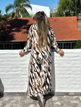 Vestido largo de lanilla color fucsia con estampado animal print negro, de corte recto y mangas largas.