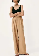 Pantalón de tiro alto con corte recto y pernera ancha, confeccionado en tela fluida color marrón. Presenta cierre frontal con cremallera y botón oculto, además de trabillas en la cintura.