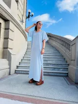 Vestido largo celeste a rayas verticales blancas, de corte recto y mangas cortas.