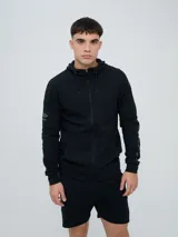 Campera deportiva Umbro modelo Terrace, color negro, con capucha y cierre frontal completo. Cuenta con bolsillos tipo canguro y detalles de la marca en las mangas.