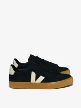 Championes Veja modelo Campo, confeccionados en gamuza negra con el logo lateral y detalle en el talón en color crema. Presentan suela de goma color caramelo y cierre con cordones negros.