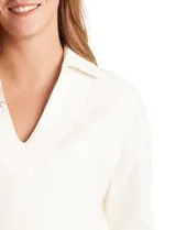 Buzo de punto suave marca Cyrus, color blanco, con cuello solapa y escote en V. Presenta diseño de hombros caídos, mangas 3/4 con puños largos de tejido rib al tono y corte holgado con tajos laterales en el ruedo.