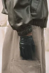 Guantes cortos de efecto piel en color negro, con costuras decorativas en el dorso y puño de tejido de punto trenzado en mezcla de lana color marrón.
