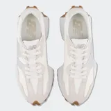 Championes New Balance 327 de diseño retro con capellada en tonos beige y off-white, con el logo 'N' lateral metalizado en color plateado, suela blanca y suela exterior de goma marrón con tacos extendidos.