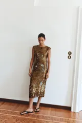 Vestido midi dorado cubierto de lentejuelas, con cuello redondo, mangas cortas y espalda abierta con cordones para ajustar.
