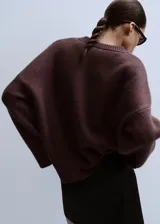 Jersey de punto color marrón oscuro, con cuello redondo y diseño oversize de manga larga.