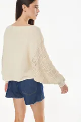 Sweater cropped de punto calado, color celeste melange, con mangas anchas de diseño holgado y cuello redondo.