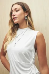 Top sin mangas color negro, con cuello alto y terminación en pico en la parte inferior, con un detalle de frunce o abertura en el lateral.