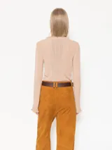 Top color beige de tejido de punto acanalado, con cuello redondo y mangas largas con volados en los puños.