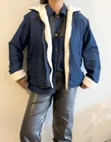 Campera azul de jean con interior de corderito blanco, cierre frontal y bolsillos laterales.