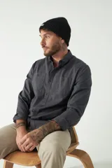 Camisa de hombre color beige con efecto stone wash, corte regular, cuello clásico, cierre frontal con botones, dos bolsillos con solapa abotonada en el pecho y mangas largas con puños abotonados.