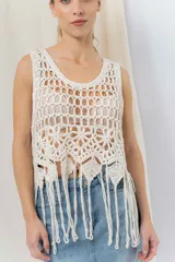 Top tejido artesanal color crudo, confeccionado en punto calado con diseño protagonista. De silueta recta y calce relajado, presenta escote amplio y terminación inferior con flecos.