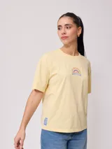 Remera color amarillo claro con estampado en el frente que incluye un sol y el texto 'Rusty Club'. Corte holgado.