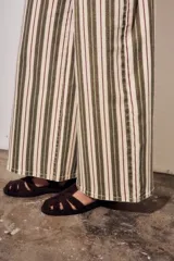 Jean wide leg de tiro alto con diseño de rayas verticales en tonos verde militar, borravino y crudo. Cuenta con bolsillos delanteros y traseros, y cierre frontal con botón y cremallera.